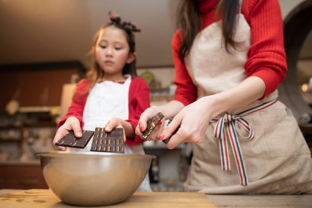 istock Mother and daughter breaking chocolate 1293183189