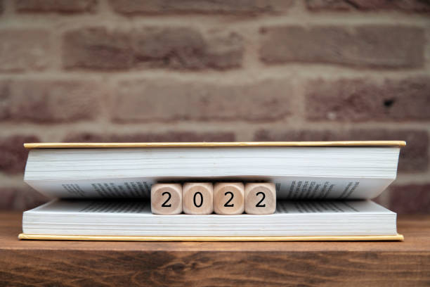 istock 2022 written on wooden blocks between book pages on a shelf. 1293183594