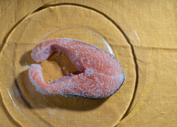 Pickling salmon steak at home on plate and a yellow tablecloth. Salt on fish. Preparings for  NeW Year holiday|!