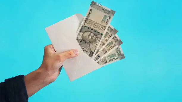 Indian Currency Rupee 500 Bank Notes in white envelope on blue background.