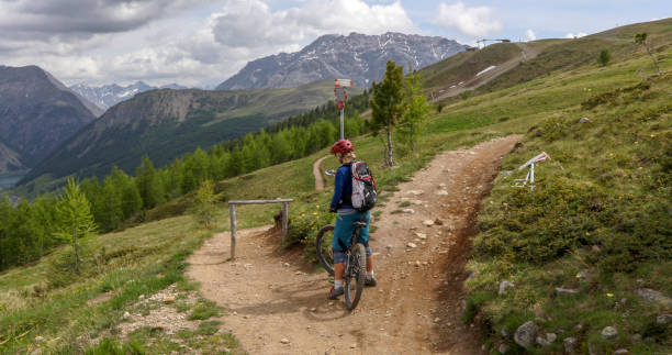Female mountain biker rides along mountain path in the morning
