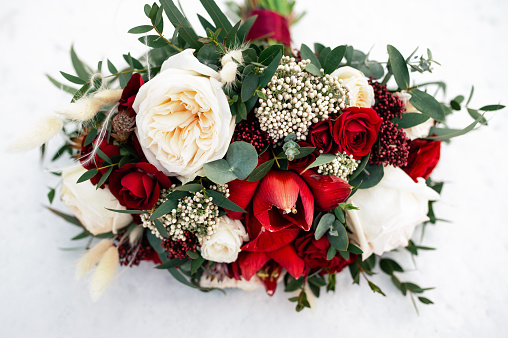 wedding bouquet of red and white flowers on snow outdoors in winter