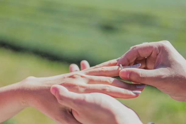 istock man wearing a ring on women's finger with green nature background 1293194429