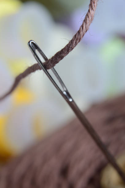 istock a sewing needle with brown thread through the eye of the needle. macro. 1293194482
