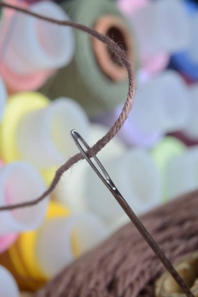 istock a sewing needle with brown thread through the eye of the needle. macro. 1293194618