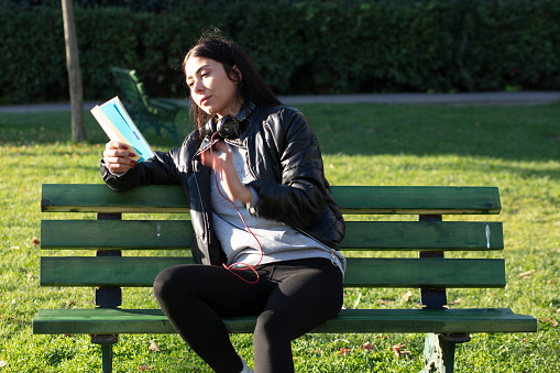 beautiful,Young woman sitting on a bench and reading book in a public park
