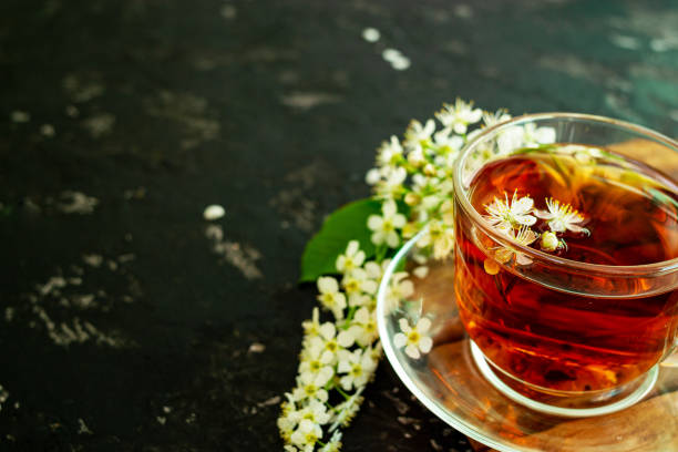 istock A cup of flower tea with spring cherry blossom on a black background. Copy space 1293197789
