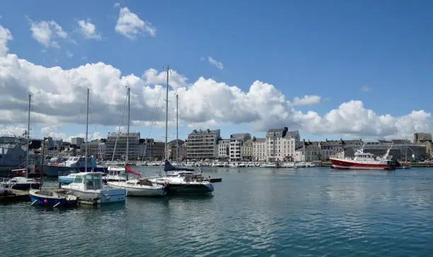 Looking across Cherbourg marina or, Bassin du Commerce, to Quay Caligny with all the boats on a bright spring day in Cherbourg. Incidental people, restaurants, shops and apartment line the Quay.