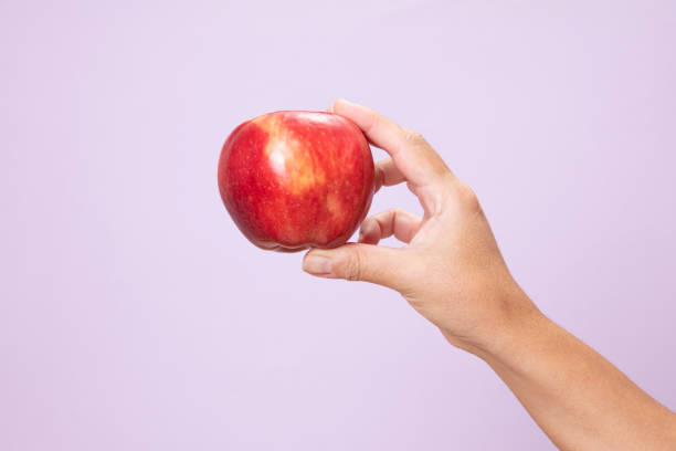istock Hand Holding Red Apple on pink paper background. 1293201897