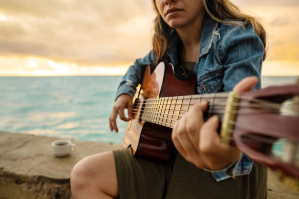 istock Woman playing guitar on the beach at sunrise 1293205908