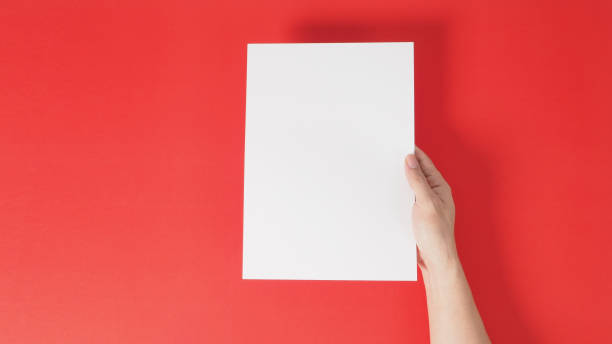istock Right hand is holding white the A4  blank paper on red background. 1293205939