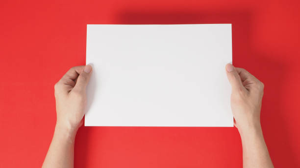 istock hands is holding the white blank  A4 paper on red background. 1293205940