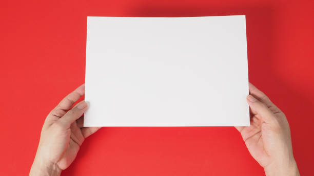istock hands is holding the white blank A4 paper on red background. 1293205946