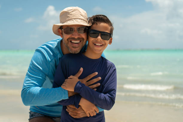 ritratto di padre e figlio sulla spiaggia tropicale - cappello per il sole foto e immagini stock