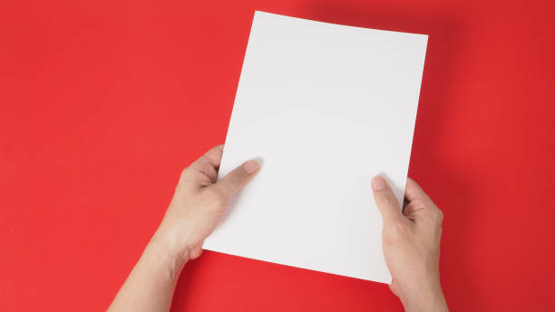 istock hands is holding the white A4 blank paper on red background. 1293205973
