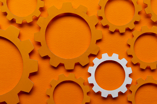 Orange color paper gears on orange background.