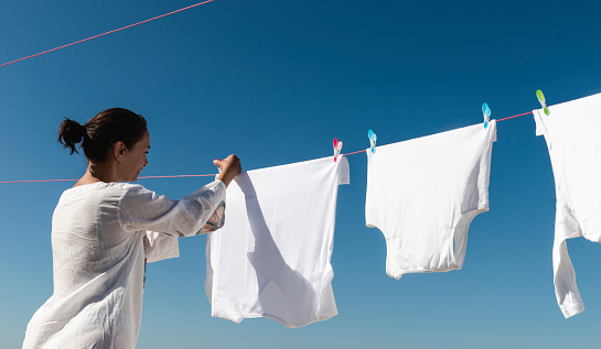 Clean clothes hanging on washing line against sky. Drying laundry