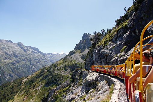 tourist train full of people running through a mountain gorge in the Pyrenees, Artouste France, rear view, horizontal