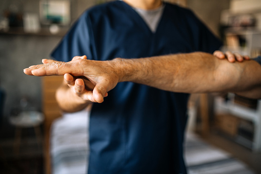 Senior man patient doing physical therapy exercises with home visiting health care physical therapist at his home