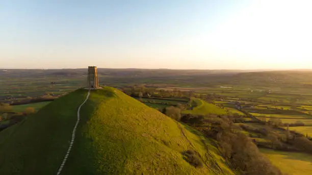 Aerial view of the early morning sunrise over Glastonbury Tor with Somerset fields below.