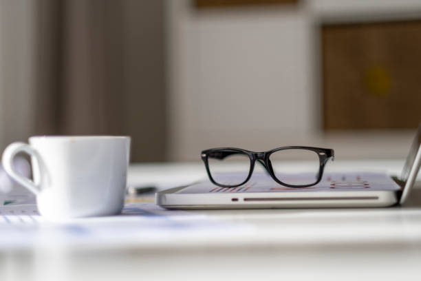 Eyeglasses on laptop keyboard with headphones and diary on woode