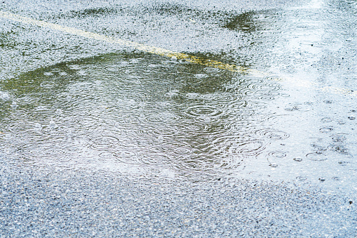 Drenching downpour late summer August rain storm parking lot puddles, bubbles and splashes