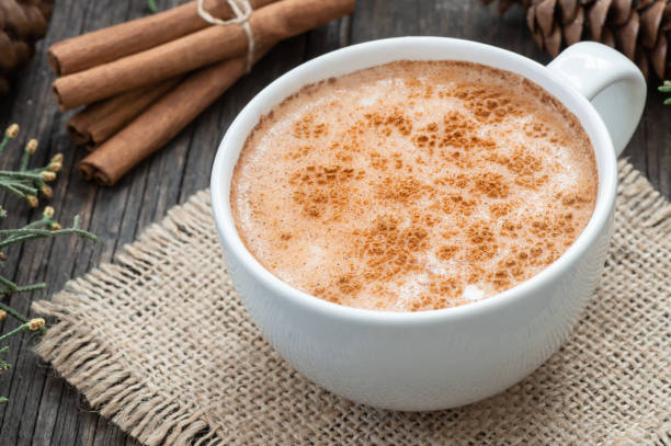 white cup of salep milky traditional hot drink of Turkey with cinnamon powder and sticks on rustic vintage wooden table. Sahlep background stock photo