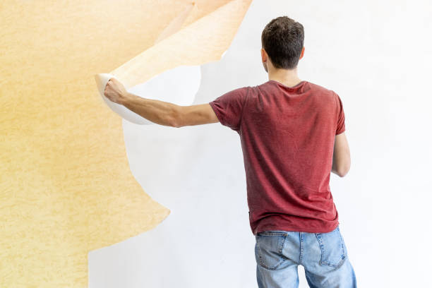 istock young man tearing old wallpaper off the wall during renovation 1293225564