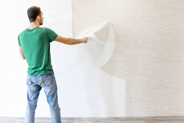 istock young man tearing old wallpaper off the wall with copy space 1293225578