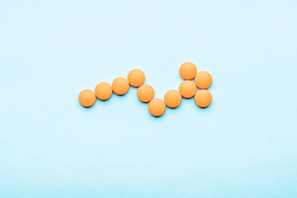 flecha de píldora naranja sobre fondo azul. espacio exterior. - pharmacy commercial sign painkiller medicine fotografías e imágenes de stock