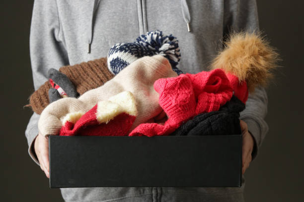 mujeres voluntarias sosteniendo caja de donación con ropa de invierno de lana caliente, sombreros, calcetines, guantes... - abrigarse fotografías e imágenes de stock
