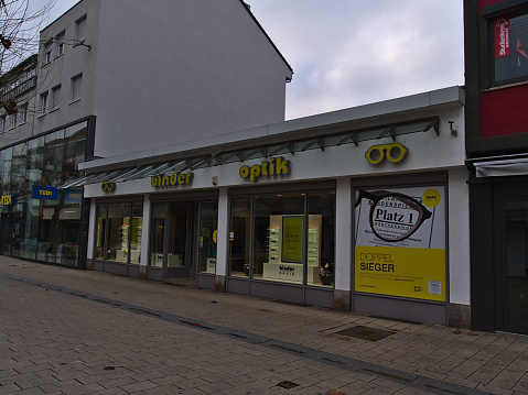 Heilbronn, Germany - 12-25-2020: Closed branch of regional optician retail chain Binder Optik in shopping street in downtown during Covid-19 lockdown with shop window and yellow colored company logo.