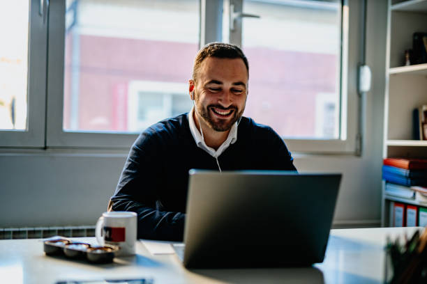 istock Man using laptop and headphones working and having a video call 1293273183