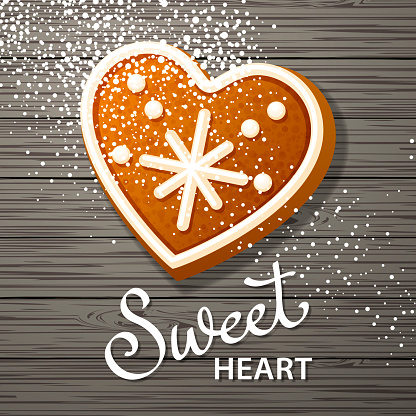 Celebrate Valentine's Day with baking powdered sugar spraying on the heart shape gingerbread cookie over the black wooden table background