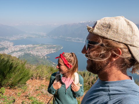 Young couple hiking in Switzerland looking at breathtaking lake view \nPeople travel and enjoying outdoors activity concept.