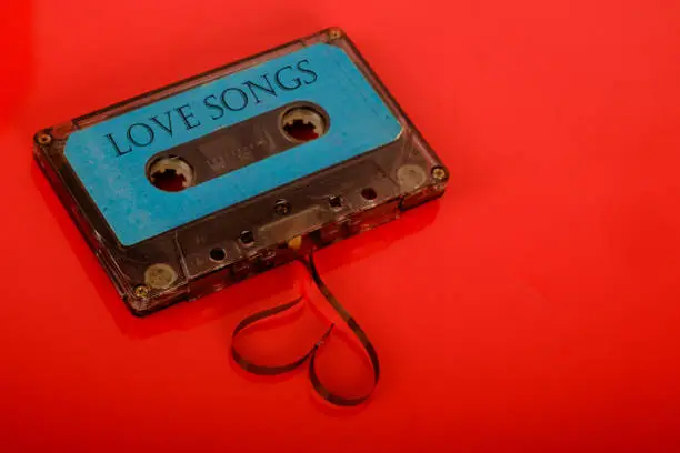 Cassette tape with a heart shape on a red background in studio