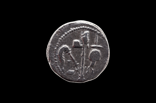 Silver Roman denarius coin replica of Roman emperor Julius Caesar celebrating his conquest of Gaul reverse showing sacrificial implements isolated on a black background, stock photo image