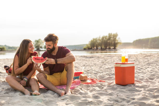 istock Romantic couple sharing a watermelon slice on a beach picnic 1293281167