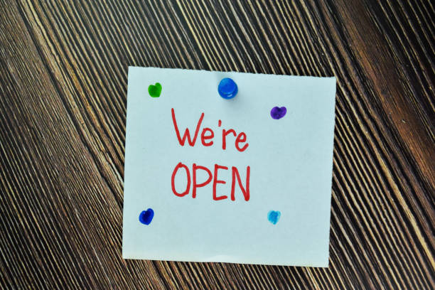 istock We're Open write on sticky note and isolated on Wooden Table. Business Concept 1293283095