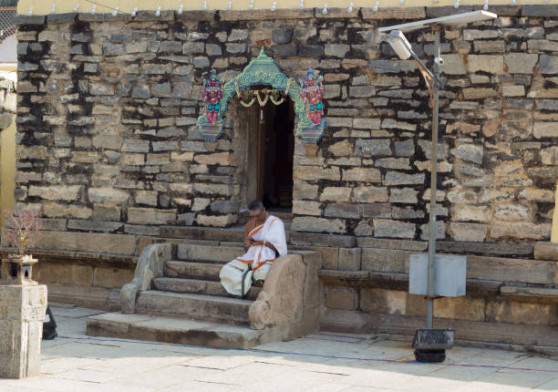 un prete indù visto immerso nella navigazione nel suo smartphone. - indian ethnicity traditional culture architecture karnataka foto e immagini stock