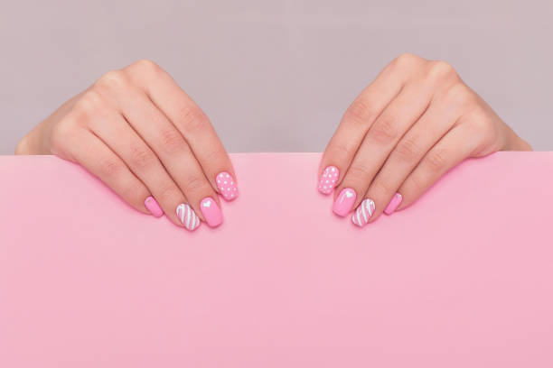 istock Female hands with pink manicure nails and Valentine's day design 1293287333