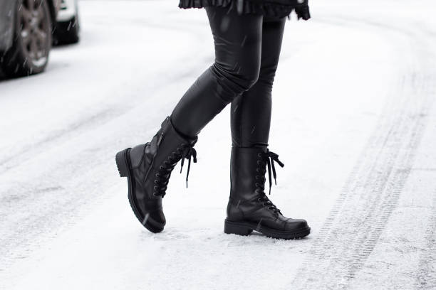 istock Female legs in black winter shoes 1293287340