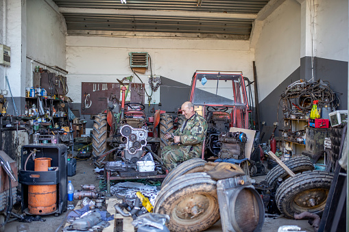 Photo of hard working mechanic in his repair garage busy with fixing tractors.