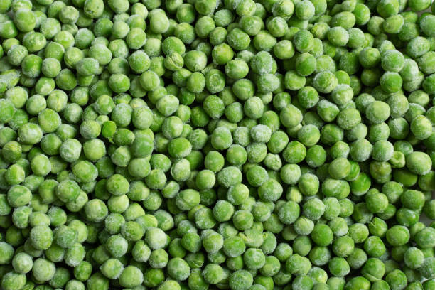 istock Fresh frozen green peas background top view. 1293289275