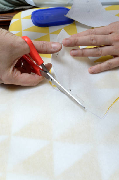 istock Women's hands cut the fabric with scissors according to the pattern on the table. 1293290456