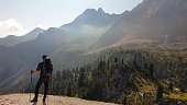 Pragser Wildsee - A man with a big hiking backpack standing at the edge of a mountain and admiring the panoramic view in front