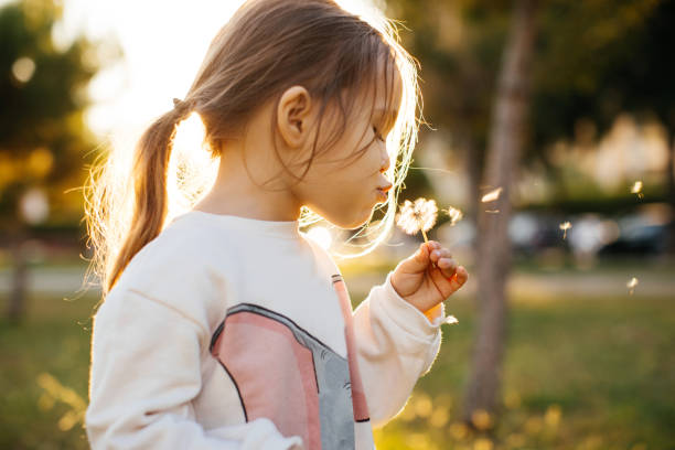 istock Happy girl blowing dandelion 1293303581