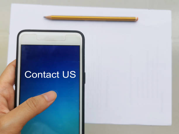 istock Holding Phone Written Contact Us On White Background 1293303834