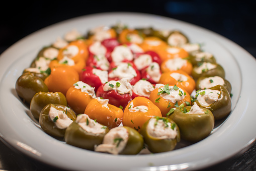 A plate full of colorful tiny peppers stuffed with cream cheese.