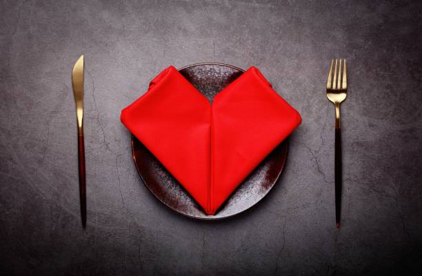 Fork and knife and Red heart napkin on the plate. Lovely food. Romantic table setting for Valentines day stock photo